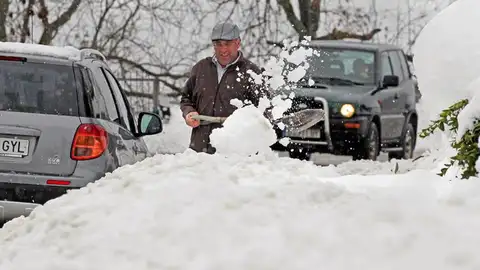 Un vecino del pueblo de Pajares (Asturias) trata de sacar su coche tras la nevada Temporal de nieve en Asturias