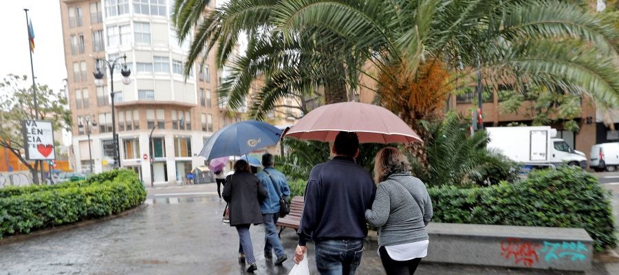 Varias personas pasean protegidas con paraguas Varias personas pasean protegidas con paraguas