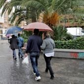Varias personas pasean protegidas con paraguas 