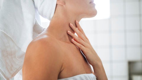 Mujer poni&eacute;ndose crema en el cuello