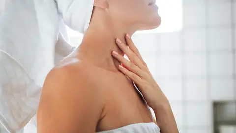 Mujer poniéndose crema en el cuello Mujer poniéndose crema en el cuello