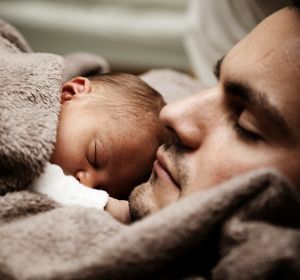 Un padre dormido junto a su bebé Un padre dormido junto a su bebé