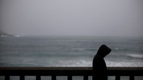 Un hombre camina bajo la lluvia por el paseo mar&iacute;timo de A Coru&ntilde;a