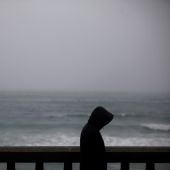 Un hombre camina bajo la lluvia por el paseo marítimo de A Coruña