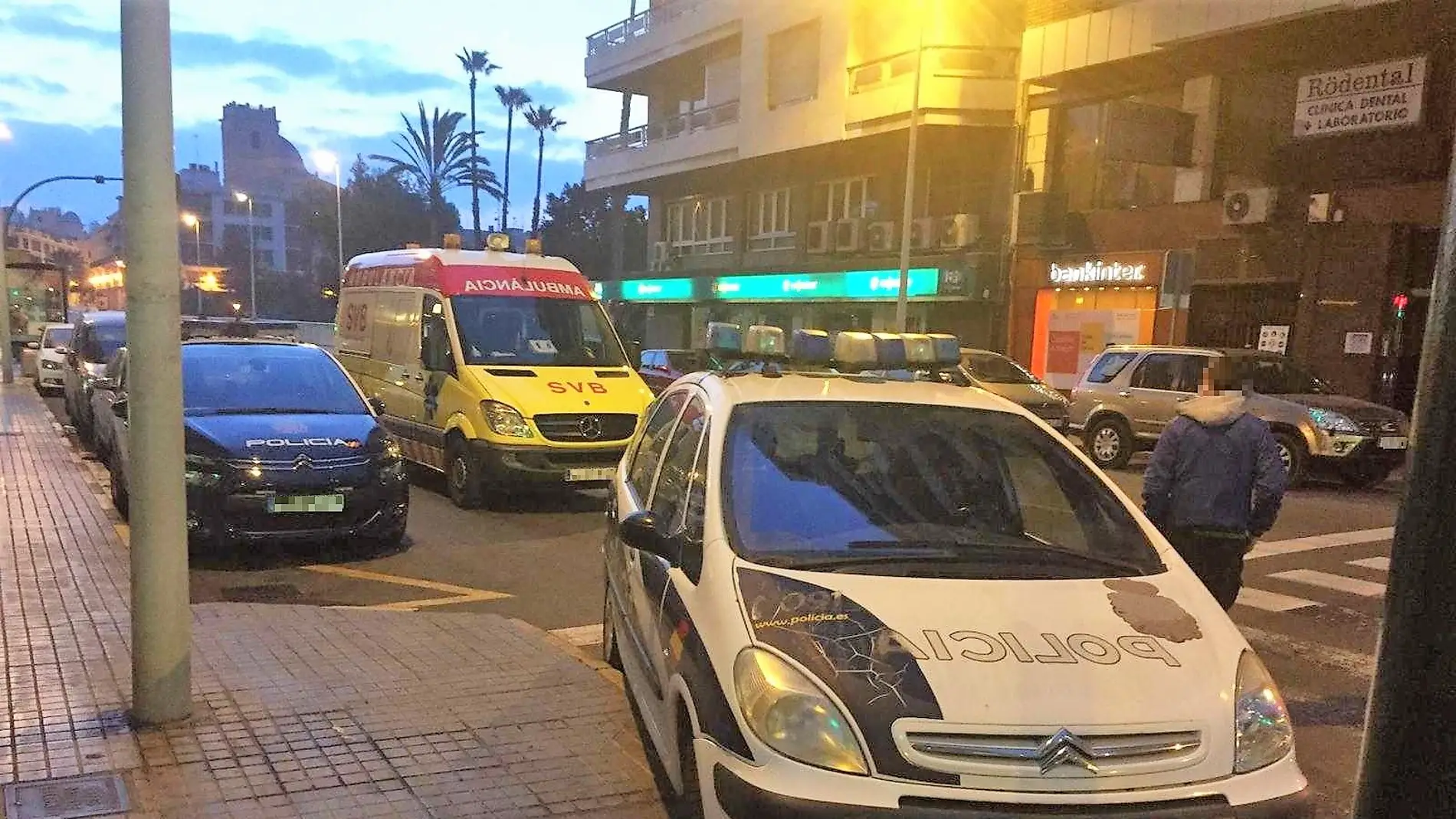 Vehículo de la Policía Nacional y ambulancia junto al edificio de la vivienda asaltada