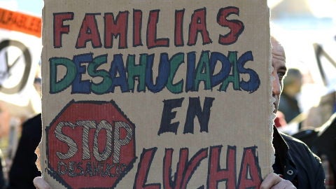 Un hombre sujeta una pancarta durante una manifestaci&oacute;n contra los desahucios