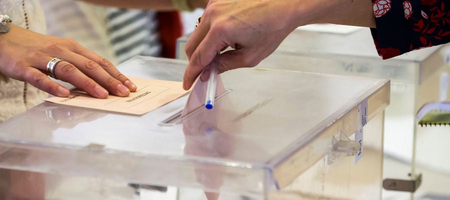 Una mujer deposita su voto en una urna electoral Una mujer deposita su voto en una urna electoral