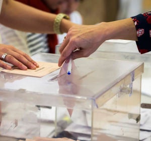 Una mujer deposita su voto en una urna electoral Una mujer deposita su voto en una urna electoral