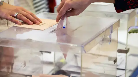 Imagen de archivo de una persona depositando un voto en una urna Una mujer deposita su voto en una urna electoral