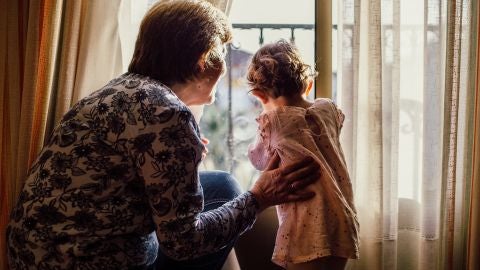 Una abuela mira por la ventana con su nieta