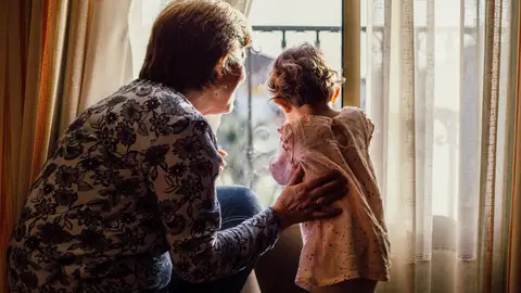 Una abuela mira por la ventana con su nieta Una abuela mira por la ventana con su nieta