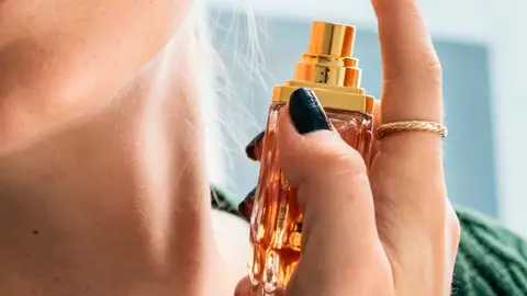 Una mujer echándose perfume Una mujer echándose perfume
