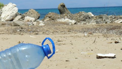 Una botella de pl&aacute;stico junto con otros residuos en una playa