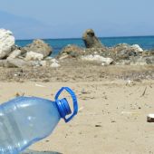 Una botella de plástico junto con otros residuos en una playa