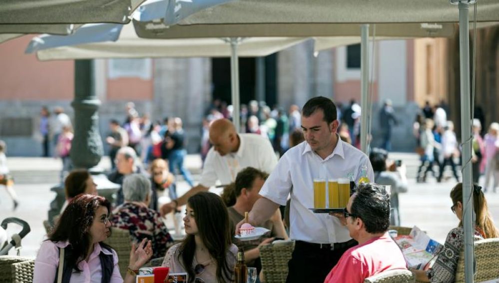 Un camarero sirve bebidas en una terraza en la plaza de la Virgen de Valencia