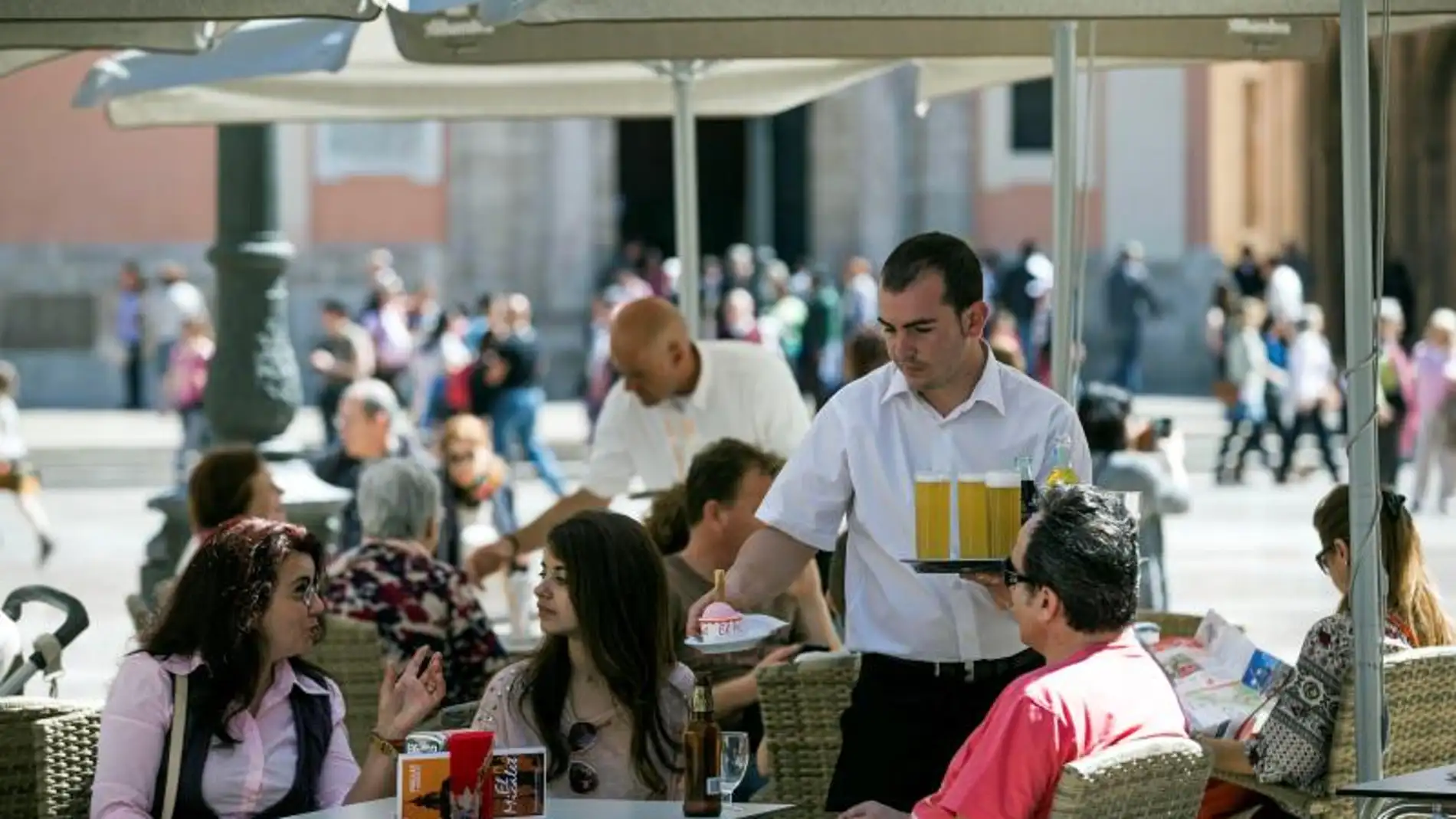 Un camarero sirve bebidas en una terraza en la plaza de la Virgen de Valencia