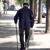 Un jubilado camina en una calle. 