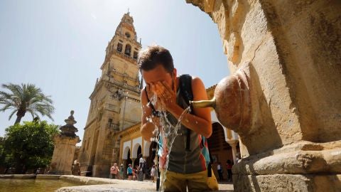 Un turista se refresca en el patio de los Naranjos de la Mezquita-Catedral de C&oacute;rdoba