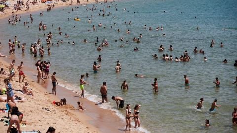 Unos ba&ntilde;istas se refrescan en la playa de la Nova Icaria de Barcelona
