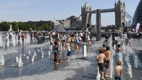 Un grupo de ni&ntilde;os combaten la ola de calor moj&aacute;ndose en una fuente frente al Puente de la Torre de Londres