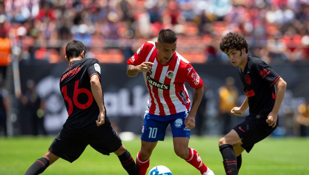 Ricardo Centurión de San Luis disputa el balón con Juan Manuel Sanabria y Sergio Camello de Atlético de Madrid