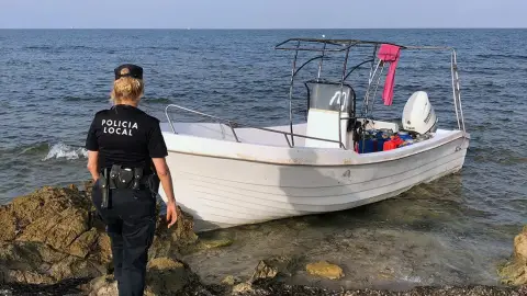 Una agente de la Policía Local de Elche junto a la embarcación con migrantes que ha llegado a la playa del Carabassí. Una agente de la Policía Local de Elche junto a la embarcación con migrantes que ha llegado a la playa del Carabassí.