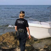 Una agente de la Policía Local de Elche junto a la embarcación con migrantes que ha llegado a la playa del Carabassí.