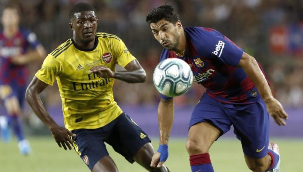 El delantero del FC Barcelona Luis Suárez (d) pelea un balón con Ainsley Maitland-Niles, del Arsenal