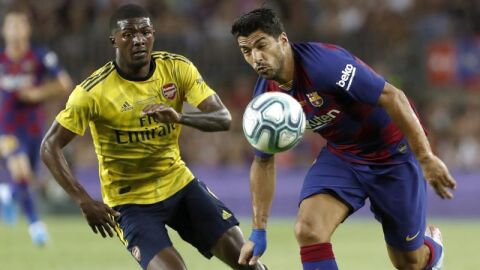 El delantero del FC Barcelona Luis Su&aacute;rez (d) pelea un bal&oacute;n con Ainsley Maitland-Niles, del Arsenal