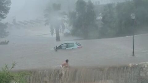 Una mujer sale a nado de su coche, en Cala d'or, atrapado por las fuertes lluvias.