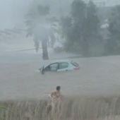 Una mujer sale a nado de su coche, en Cala d'or, atrapado por las fuertes lluvias.