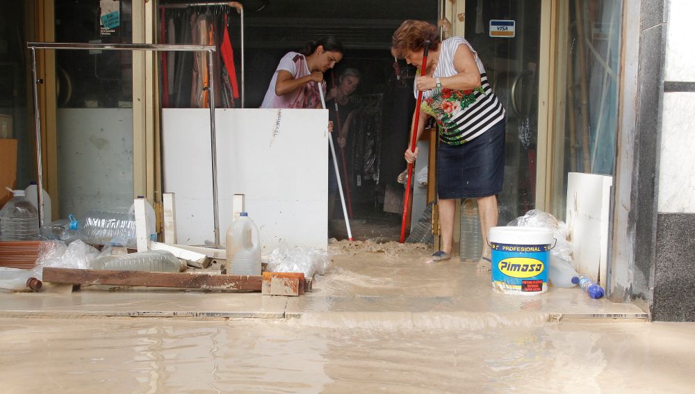 Vecinos de Orihuela limpian sus casas y negocios anegados por la avenida de agua povocada por el desbordamiento del río Segura tras la gota fría.