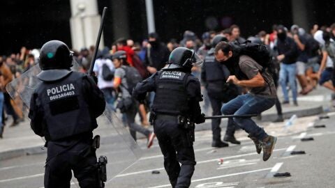 Miembros de los Mossos d'Esquadra cargan contra los centenares de personas que se agolpan ante el Aeropuerto del Prat
