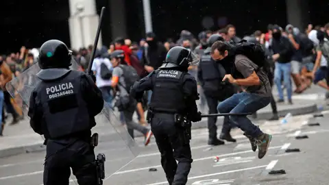 Miembros de los Mossos d'Esquadra cargan contra los centenares de personas que se agolpan ante el Aeropuerto del Prat Miembros de los Mossos d'Esquadra cargan contra los centenares de personas que se agolpan ante el Aeropuerto del Prat