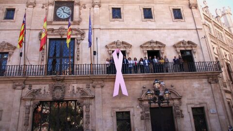 Una gran lazo rosa cuelga de la fachada del Ayuntamiento de Palma, con motivo del D&iacute;a Mundial contra el c&aacute;ncer de mama 