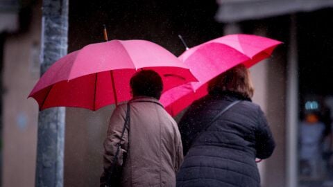 Dos mujeres ser protegen de la lluvia en las calles de Ourense, Galicia