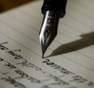 Imagen de archivo de una pluma escribiendo una nota Imagen de archivo de una pluma escribiendo una nota