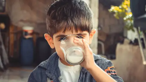 Niño bebiéndose un vaso de leche Niño bebiéndose un vaso de leche