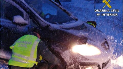 Una agente de la Guardia Civil auxilia a un veh&iacute;culo atrapado en la nieve en Villena.