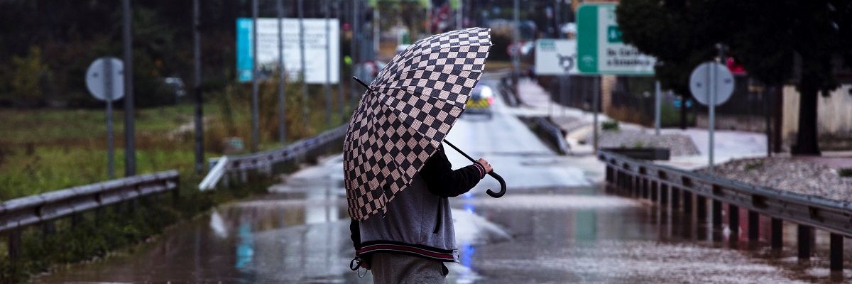 Un hombre se resguarda de la lluvia con un paraguas Un hombre se resguarda de la lluvia con un paraguas