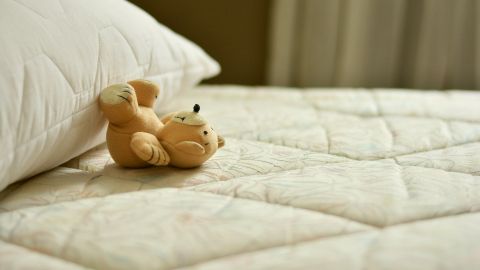 Imagen de archivo de una cama con un oso de peluche. 