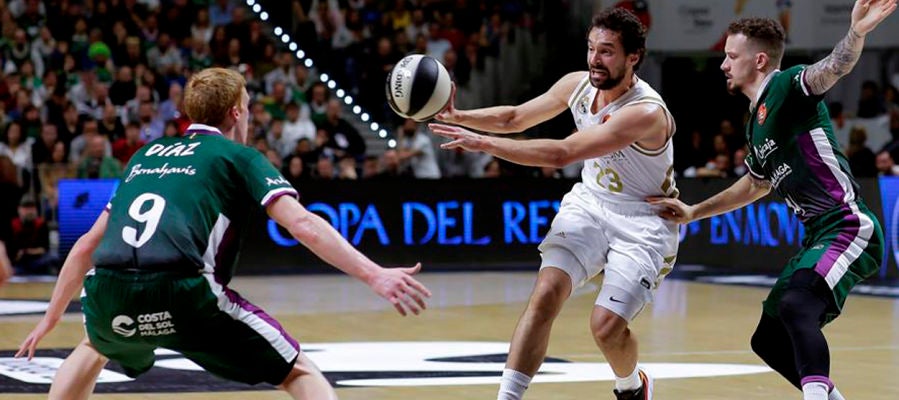 El base Sergio Llull del Real Madrid realiza un pase ante los jugadores del Unicaja Málaga, el base Alberto Díaz y el base estadounidense Josh Adams. El base Sergio Llull del Real Madrid realiza un pase ante los jugadores del Unicaja Málaga, el base Alberto Díaz y el base estadounidense Josh Adams.
