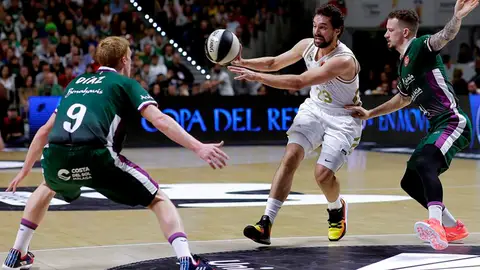 El base Sergio Llull del Real Madrid realiza un pase ante los jugadores del Unicaja Málaga, el base Alberto Díaz y el base estadounidense Josh Adams. El base Sergio Llull del Real Madrid realiza un pase ante los jugadores del Unicaja Málaga, el base Alberto Díaz y el base estadounidense Josh Adams.