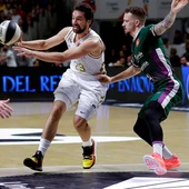El base Sergio Llull del Real Madrid realiza un pase ante los jugadores del Unicaja Málaga, el base Alberto Díaz y el base estadounidense Josh Adams. El base Sergio Llull del Real Madrid realiza un pase ante los jugadores del Unicaja Málaga, el base Alberto Díaz y el base estadounidense Josh Adams.