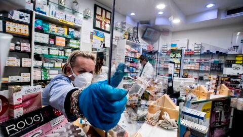 Una farmacia protege con plexigl&aacute;s al personal durante el cierre de emergencia debido al brote de coronavirus en Roma