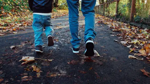 Un niño paseando junto a su padre Un niño paseando junto a su padre