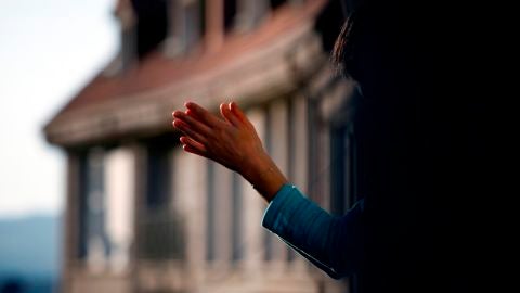 Imagen de una mujer aplaudiendo en un balc&oacute;n durante la crisis por coronavirus