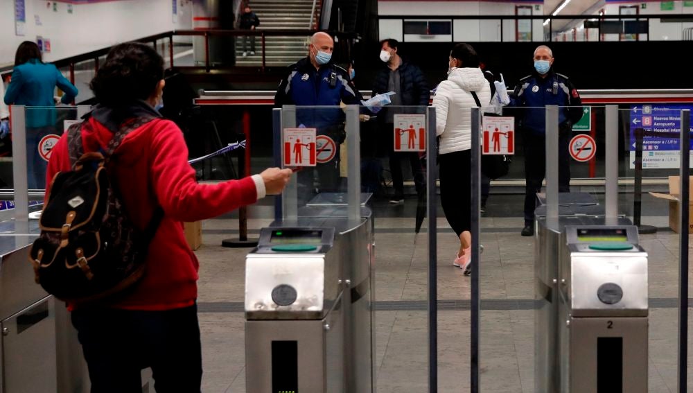 Policías entregan mascarillas en la estación de metro de Nuevos Ministerios en Madrid
