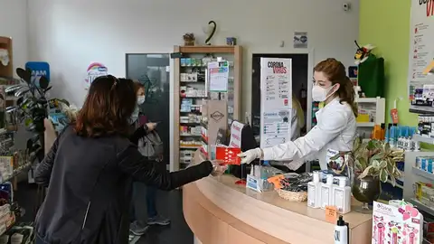 Una farmacéutica entrega una mascarilla en una farmacia madrileña Una farmacéutica entrega una mascarilla en una farmacia madrileña