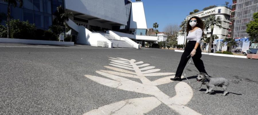 Una mujer con mascarilla pasea a su perro por la explanada que se extiende ante el Palais des Festivals de Cannes Una mujer con mascarilla pasea a su perro por la explanada que se extiende ante el Palais des Festivals de Cannes